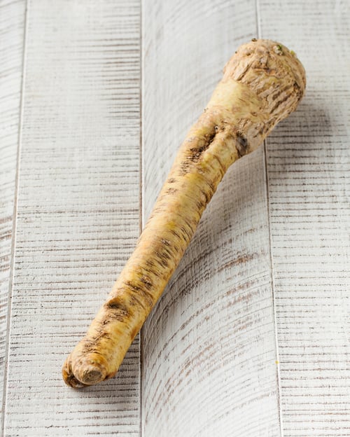 Preview: Fragrant horseradish root on a white wooden background.