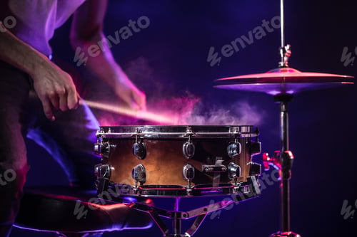 Preview: The drummer plays the drums. Beautiful blue and red background, with rays of light.