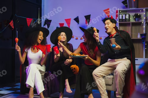 Preview: Dinner and group of people celebrating together at Halloween party.