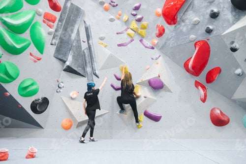 Preview: Woman On Climbing Wall At Indoor Activity Centre Receiving Personal Lesson From Coach