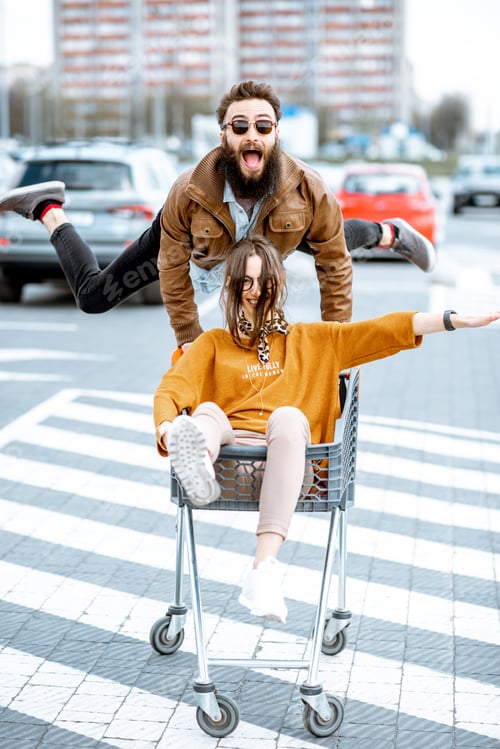 Preview: Couple riding with shopping cart on the parking outdoors
