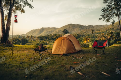 Preview: A tent on the grass with a view of the mountains in the background and sunlight.