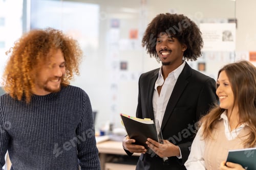 Preview: Diverse team smiling and sharing ideas at work.