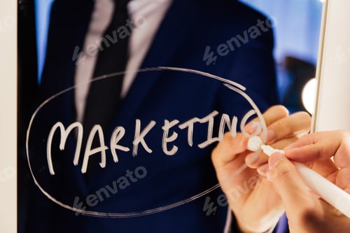 Preview: Smart business man writing the word Marketing on the mirror board