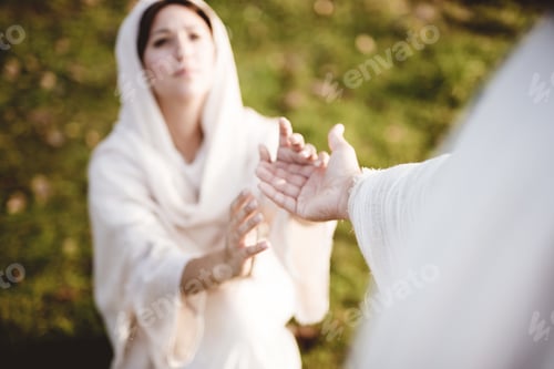 Preview: High angle shot of a female down on her knees reaching towards the hand of Jesus Christ for help