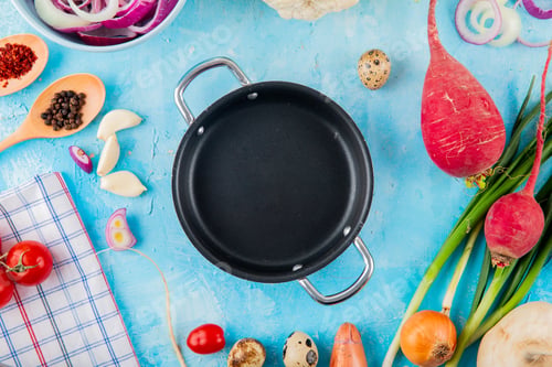 Preview: close-up view of vegetables as garlic, onion, radish with spices and braiser pan on center on blue