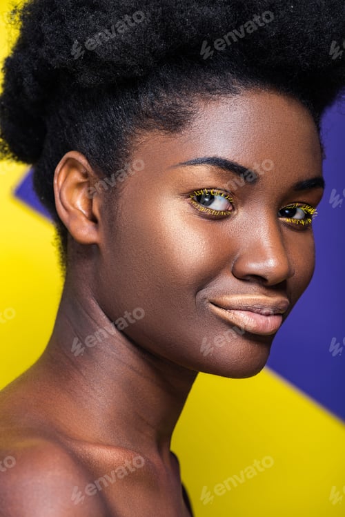 Preview: Smiling pretty african american woman looking at camera on yellow and purple