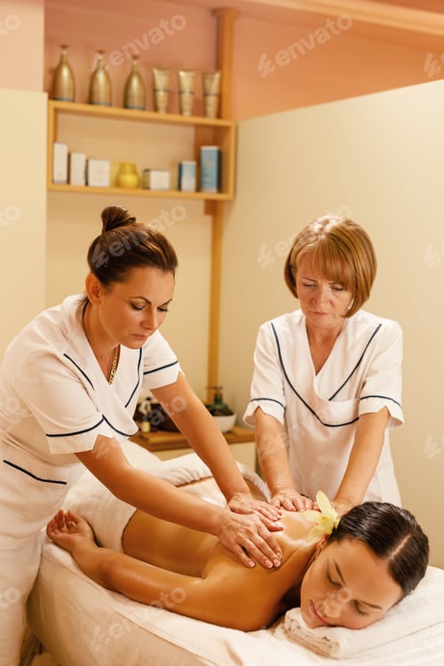 Preview: Female therapists massaging woman's back at wellness center.
