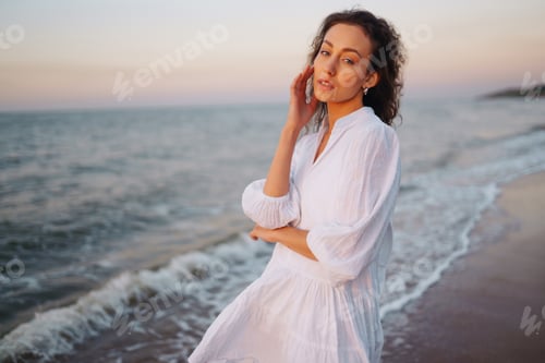 Preview: Stylish woman in elegant white dress posing near the sea. People, freedom, lifestyle, travel.