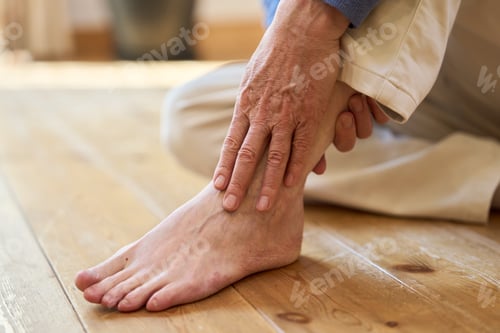 Preview: Senior Asian man holding his painful ankle
