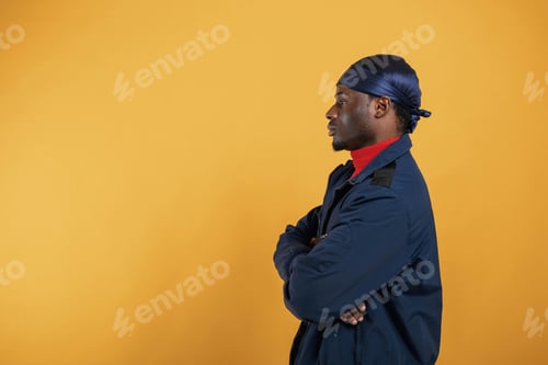 Preview: View from the side. Handsome black man is in the studio against yellow background
