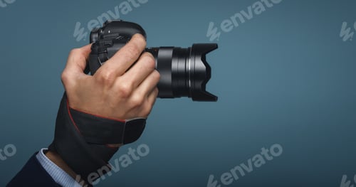 Preview: Photographer hand holding dslr camera on blue modern backround