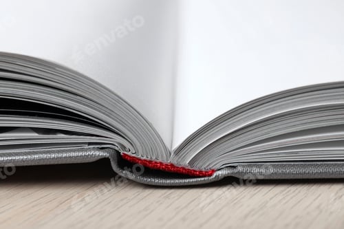 Preview: Open book with hard cover on wooden table, closeup
