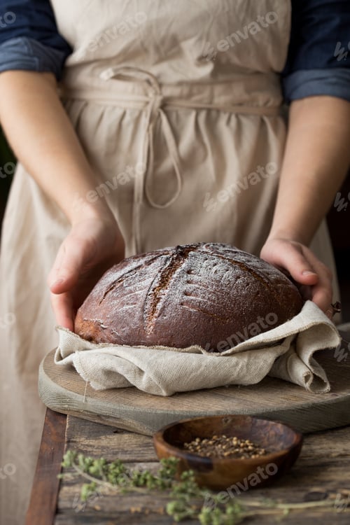 Preview: Woman baker's holding hot sourdough bread closeup