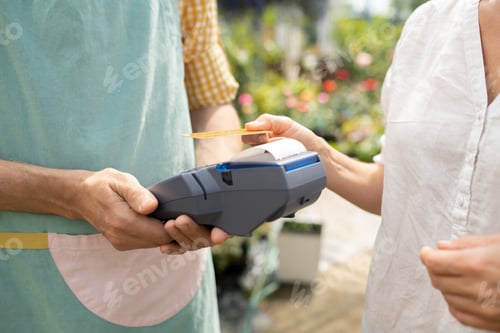 Preview: Young client of garden center paying for her purchase by credit card