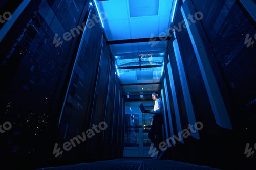 Preview: Server technician working with laptop in walkway of data facility
