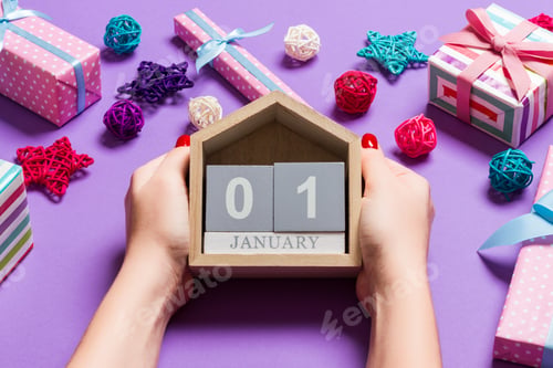 Preview: Top view of female hands holding calendar on purple background.
