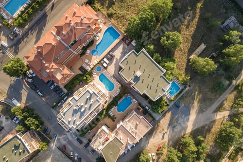 Preview: Top down aerial view of hotels roofs, streets with parked cars and swimming pools with blue water in