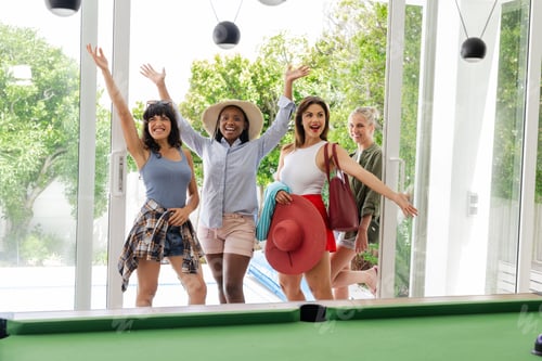 Preview: Joyful women entering modern home, smiling and waving, ready for fun day