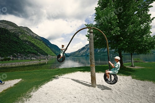 Preview: Two brothers ride on a swing from car tires at Hallstatt, Austria.