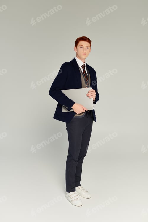 Preview: Stylish young student with red hair in elegant winter attire poses confidently in studio