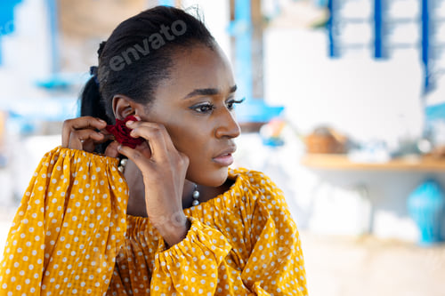 Preview: Portrait of beautiful African American model girl in yellow dress puts on jewelry earrings in his ea