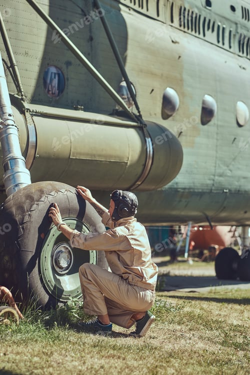 Preview: Mechanic in uniform and flying helmet wash large military helicopter.