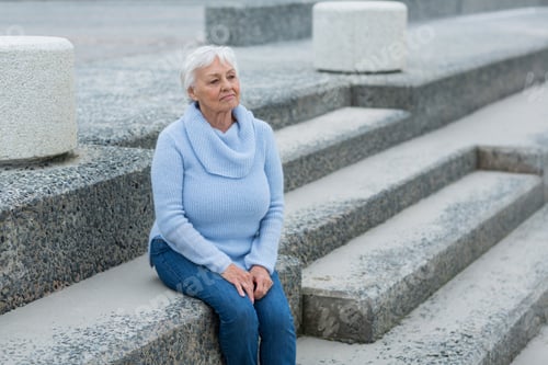 Preview: Thoughtful senior woman sitting on the steps