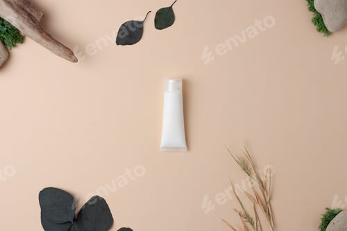 Preview: White tube of cosmetic cream with flowers on pastel beige background. Flat lay