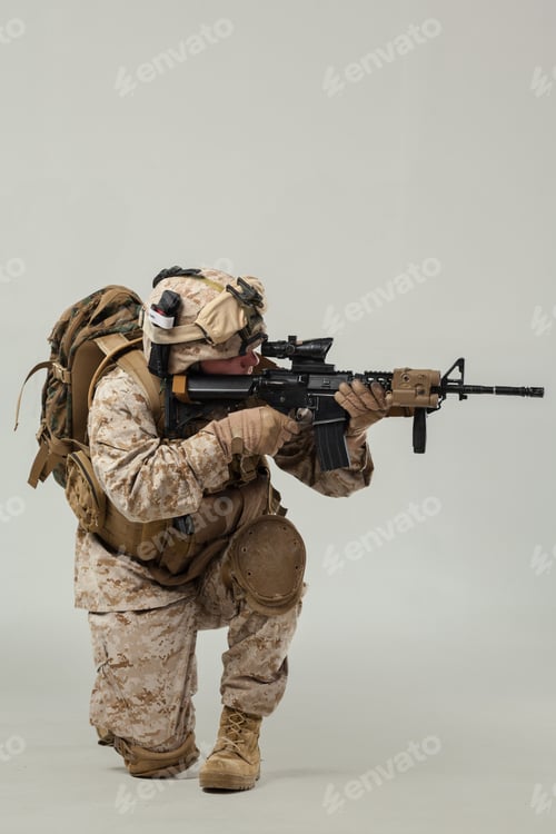 Preview: Soldier in combat gear kneels while aiming a rifle during training exercise