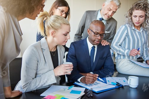 Preview: Diverse group of executives discussing paperwork around a boardroom table