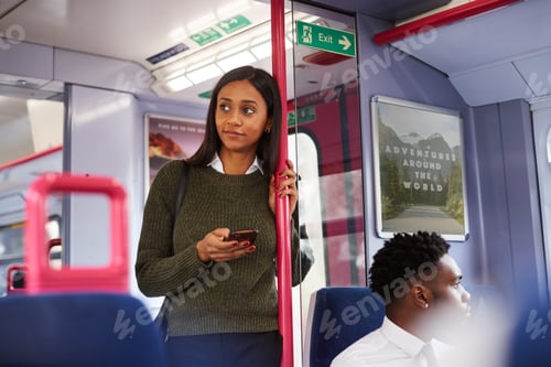 Preview: Female Passenger Standing By Doors In Train Using Mobile Phone