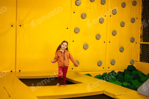 Preview: Little girl kid jumping on trampoline at yellow playground park.