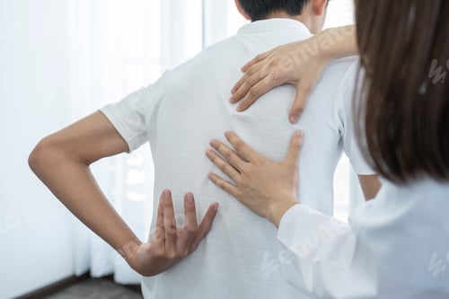 Preview: Woman doctor hands doing physical therapy By extending the back of a patient man
