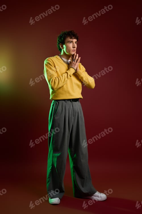 Preview: Stylish man in vibrant outfit poses against a moody backdrop with a confident expression
