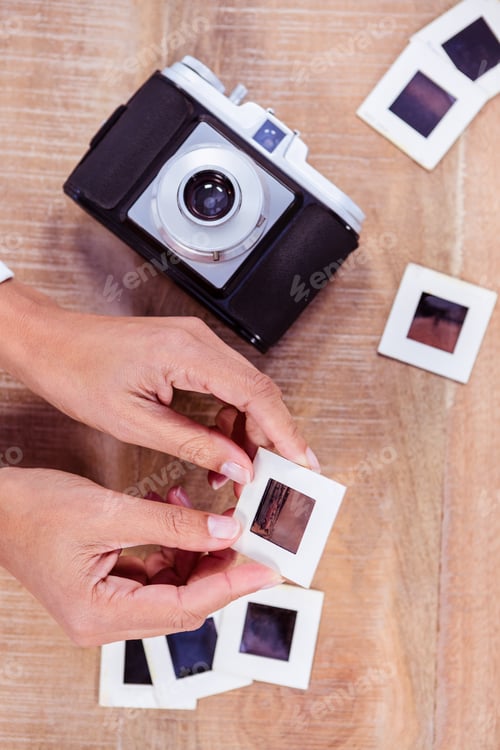 Preview: View of hands holding photo slides against wooden plank