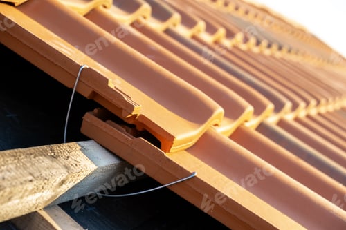 Preview: Closeup of metal montage anchor for installation of yellow ceramic roofing tiles