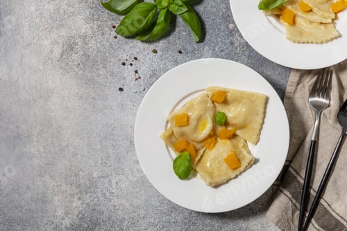 Preview: Homemade Italian pumpkin ricotta ravioli on a gray stone tabletop.