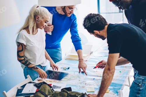 Preview: Group of diverse friends reading paper map on table
