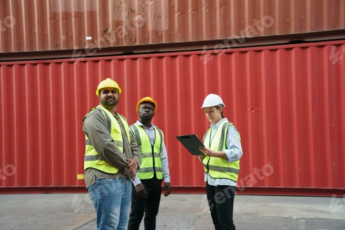 Preview: Three construction workers collaborating near shipping containers during daylight hours