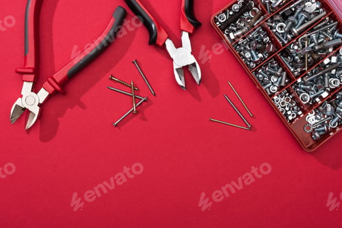 Preview: Top view of tool box with pliers and nails on red surface
