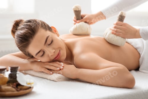 Preview: Masseuse making body massage with herbal compress balls