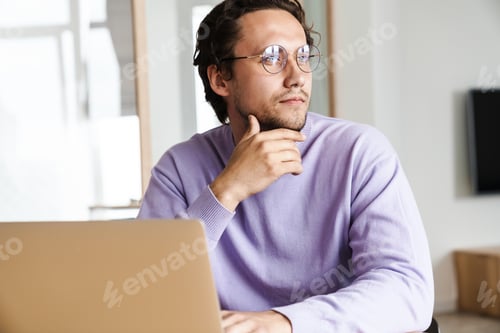 Preview: Attractive young man sitting at the kitchen table