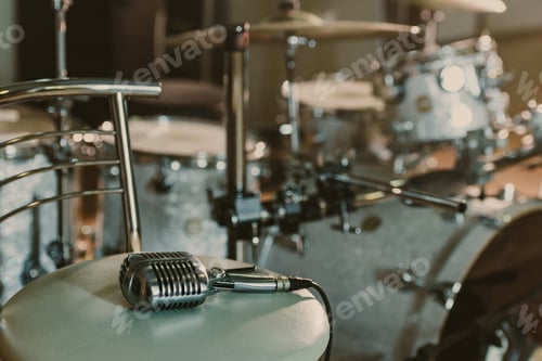 Preview: vintage microphone lying on chair in front of drum set