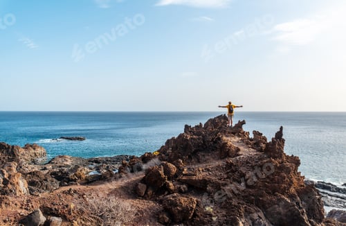 Preview: Tourist with open arms on a volcanic trail on the beach of Tacoron on El Hierro, Canary Islands