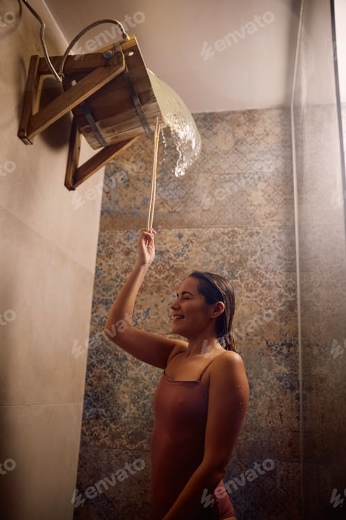 Preview: Happy woman taking shower after sauna at wellness spa.