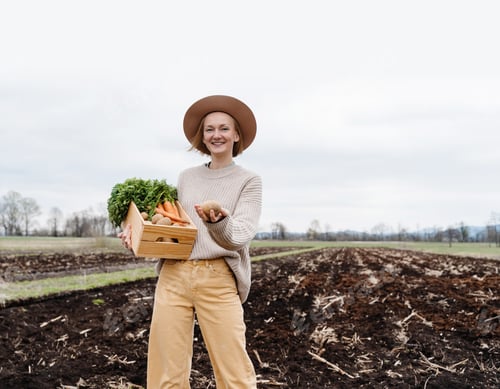 Preview: Woman standing proud with freshly bunch harvest outdoors.