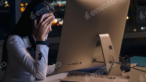 Preview: Stressed young Asian businesswoman working overtime at the office.
