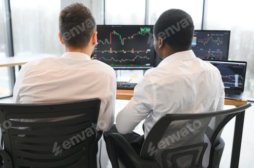 Preview: Two diverse colleagues traders talking to each other, sitting in the office