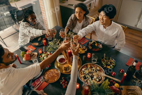 Preview: Group of happy friends is drinking wine and clinking glasses having holiday dinner party at